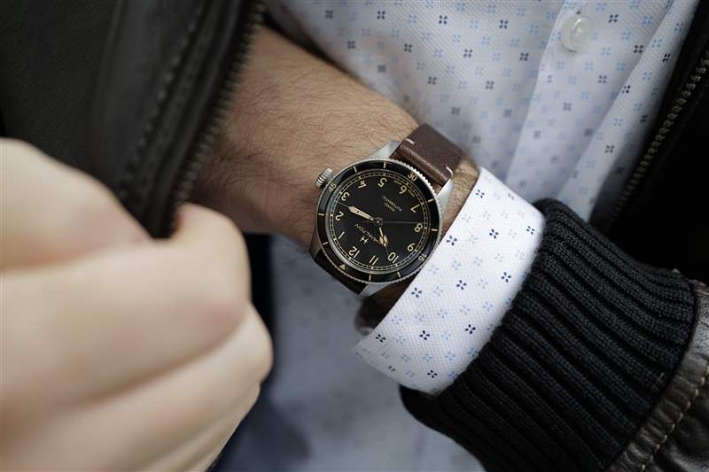 38 毫米尺寸的 Hamilton Khaki Pilot Pioneer 戴在手腕上，手伸進棕色皮夾克的口袋里。