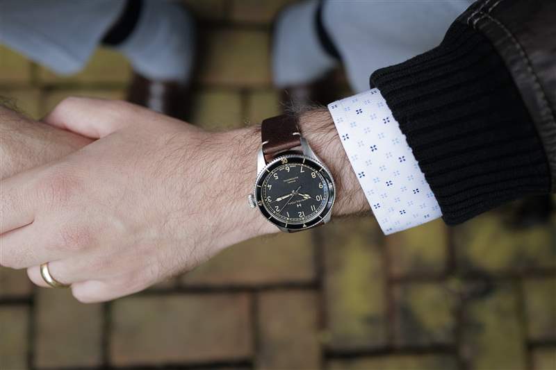 38 毫米尺寸的 Hamilton Khaki Pilot Pioneer 手腕交叉佩戴棕色皮夾克。